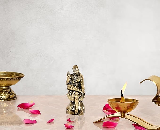 A bronze-colored brass statue of Shirdi Sai Baba seated in a cross-legged position