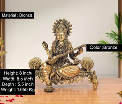 Bronze seated deity idol holding a long flute-like instrument, ornate jewelry and halo