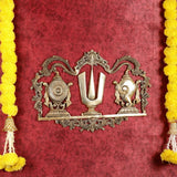 Brass wall hanging with shankh on left, chakra wheel on right, and central Namah U