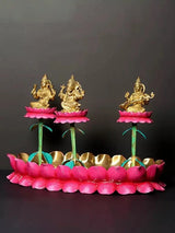 Three brass deity figures on pink lotus petals with teal stems and golden ring base