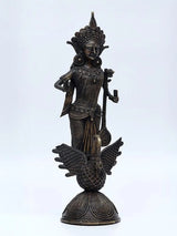 Standing Saraswati statue with ornate crown and staff, on carved swan pedestal