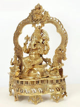 Brass Ganapati seated with raised hand, kirtimukha arch throne, detailed figures