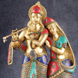 Radha Krishna brass figurine close-up, jeweled crowns, Radha in teal-red sari, flute