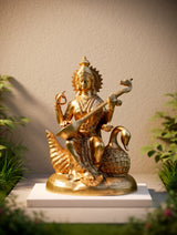 Brass Saraswati idol on swan, holding veena; ornate crown and arm bracelets
