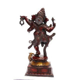 Dancing Ganesha figurine from side view, trunk raised, multi-armed pose on base