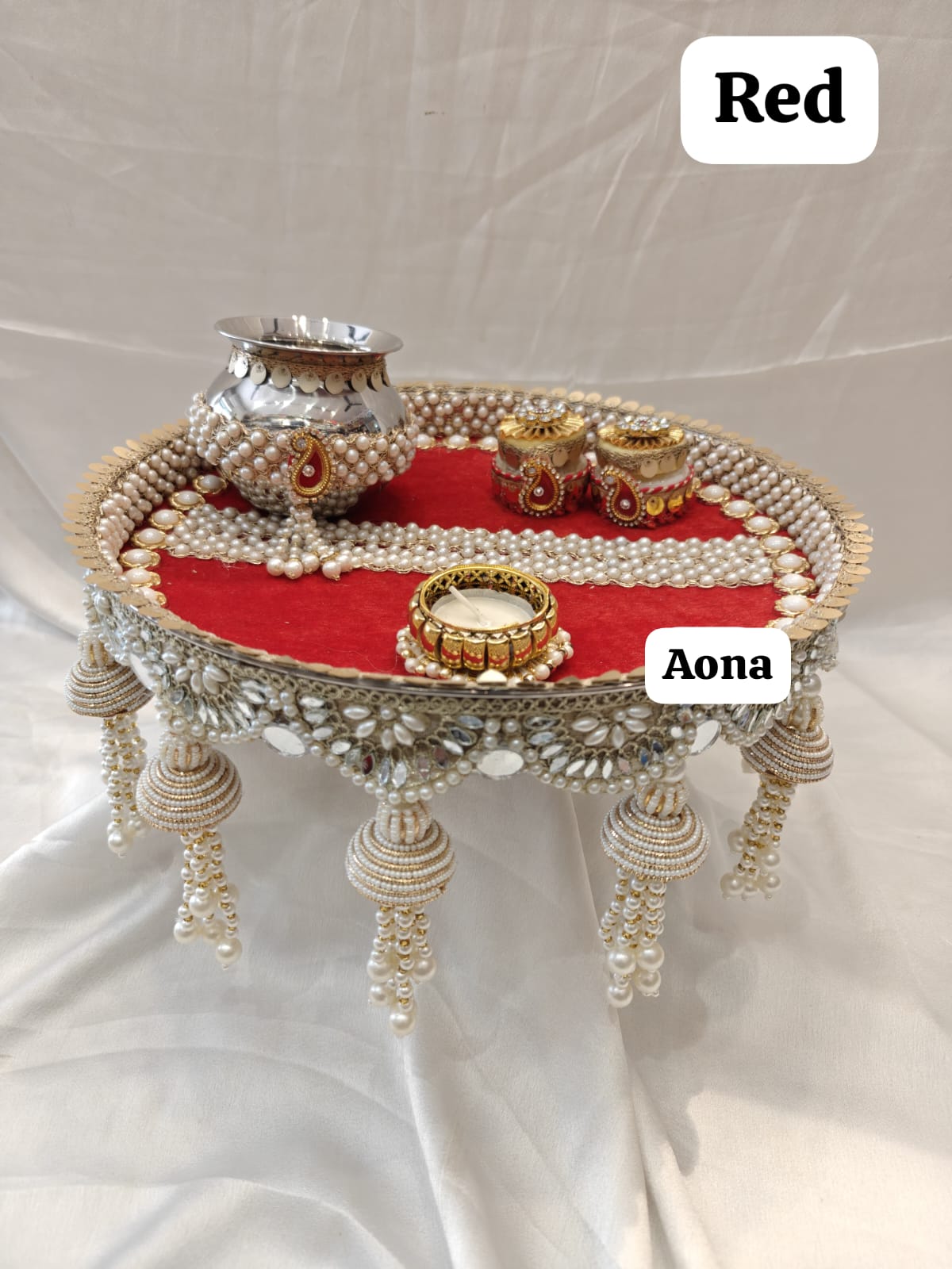 Red steel pooja thali with pearl border, ornate handles, and central diya stand