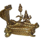 Golden brass idol reclining on patterned serpent bed, multi-armed deity with staff