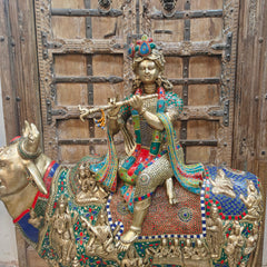 Close view of brass Govinda idol with jeweled crown, seated on decorated holy cow
