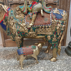 Brass holy cow statue base with standing calf and colorful fabric-like adornments