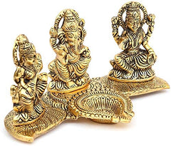 Close view of gold Ganesha Lakshmi Saraswati idol on banana leaf base, 11 cm