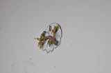Small gold-tone bird wall decor on branch, round white backplate from side angle