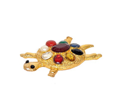 Small gold tortoise figurine with red, yellow, and crystal-like stones across the shell.
