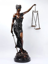 Brass Lady Justice statue angled view, scales held aloft and sword in other hand.