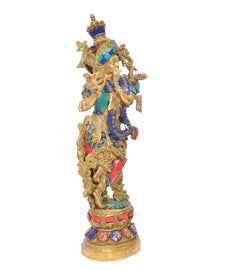 Brass Krishna idol figurine in profile with flute, teal and red patterned clothing