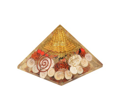 Orgonite chakra pyramid with gold spire, red stones, and white shell swirl details