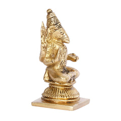 Brass tone deity idol statue, angled side view, seated with one arm raised