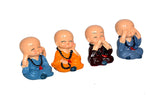 Four small seated Buddha monk idols in resin, orange and blue robes, hands together