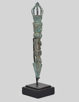 Side view of vintage bronze phurpa dagger with stacked deity heads and pointed blade