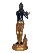 Back view of black Krishna idol statue playing flute; gold dhoti details and peacock base