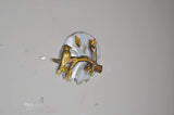 Iron birds sitting on branch wall decor with gold-tone accents on circular white backplate
