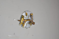 Iron birds sitting on branch wall decor with gold-tone accents on circular white backplate