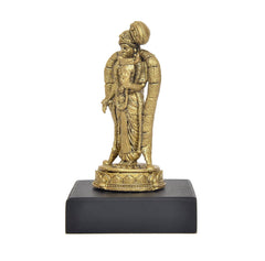 Golden side view of standing deity idol with crown and long draped robe