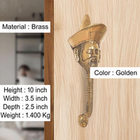 Golden brass man-face door handle on light wood, sculpted turban and beard
