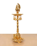Golden peacock diya stand showing top figure, hanging bells, and elephant base