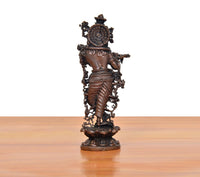 Copper-toned Krishna playing flute statue, back view on scalloped pedestal base.