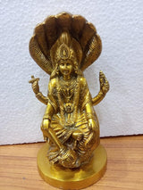 Gold-toned seated Vishnu idol with multi-hood cobra behind, raised hands, on round base