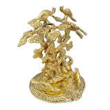 Gold-tone Radha Krishna statue under tree, side view with ornate birds and floral trim
