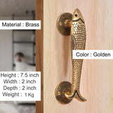 Golden brass fish-shaped door handles with textured scales and round rosettes.