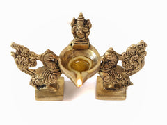 Close view of brass Ganesha diya bowl with peacock duo bases and flame