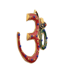 Brass OM sculpture angled view, showing red 3 loop and green 0 with bead detailing