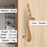 Brass peacock door handle, golden finish; mounted on light wood door surface