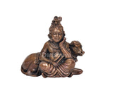 Bal Gopal copper idol with cow head behind, seated, front view angle