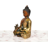 Side view of multicolor brass Buddha statue, seated with Varada mudra gesture
