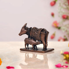 Copper cow statue with calf, three-quarter view, textured dark bronze surface and hooves
