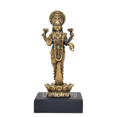 Standing Lakshmi statue, gold-toned figure with crown, detailed dress on black pedestal