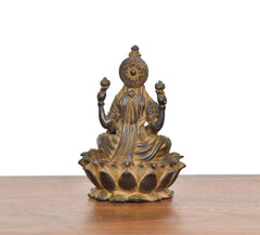 Copper Lakshmi idol, full seated form with four arms and round ornamented halo