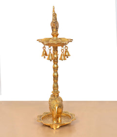 Golden metal diya stand with peacock figure, hanging lamps, and elephant base