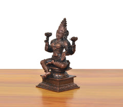 Copper Lakshmi idol from the side, four arms holding symbolic poses, seated on base.