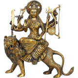 Golden antique Durga idol statue seated on lion with weapons and circular shield
