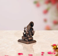 Side view of Ganesha copper idol with raised hands and round halo