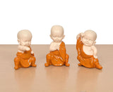 Three small seated monk Buddha resin sculptures, orange robes and bald heads