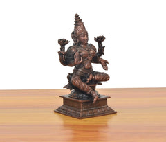 Copper Lakshmi idol viewed from another angle, seated with four arms and ornate base.