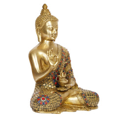 Brass Buddha statue side view; raised blessing hand; red and blue inlay accents