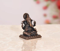 Ganesha copper murti with raised arms and patterned pedestal, dark bronze finish