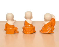 Back view of three seated monk Buddha resin sculptures in orange robes