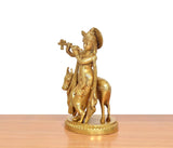 Brass Krishna playing flute, cow idol behind, golden finish on round pedestal